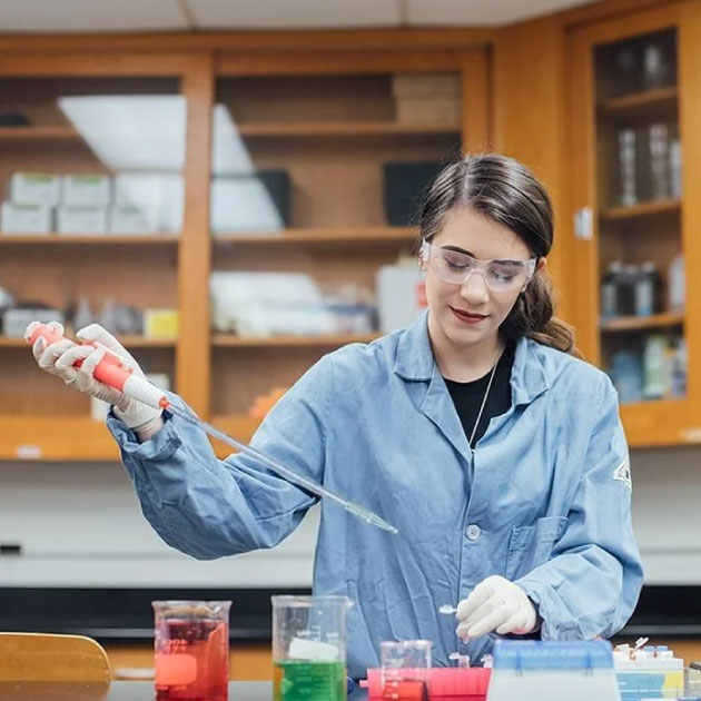 A student in a lab coat conducts an experiment